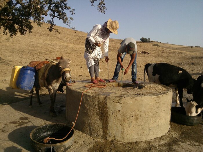 Männer holen Wasser aus einem Brunnen