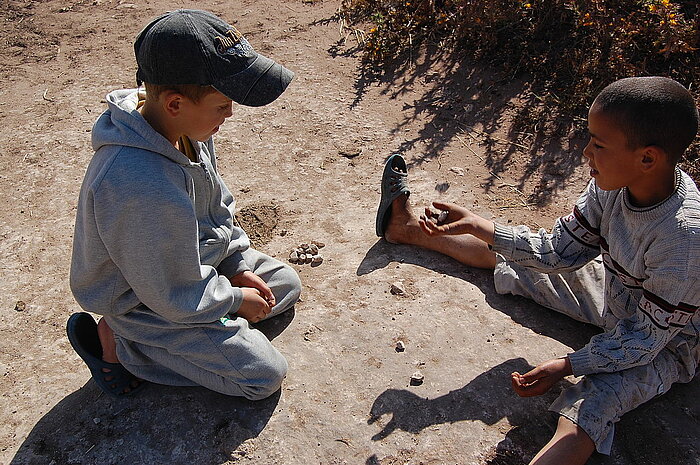 Kinder spielen mit Steinen in Marokko